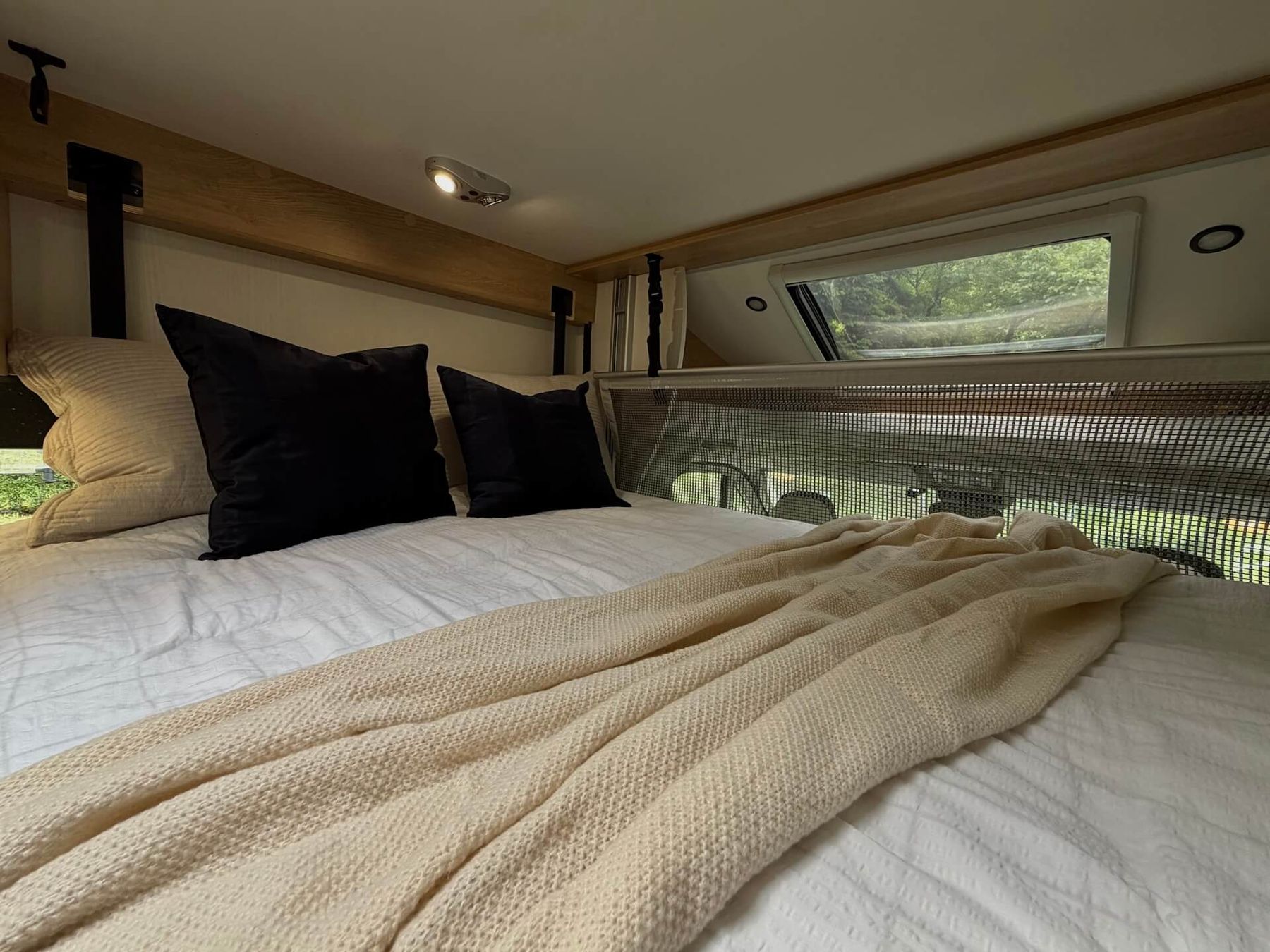 Camper Moovy - drop-down double bed above the living area with cozy bedding and pillows